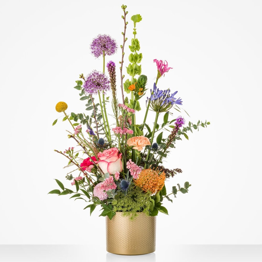 Een gouden pot gevuld met bloemen zoals een roos, anjer, eucalyptus en meer.